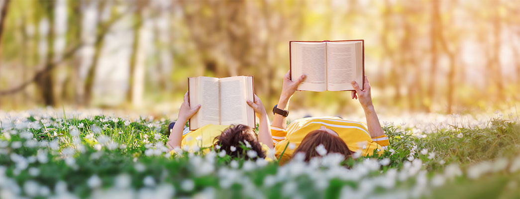 Menschen die im Gras liegen und lesen