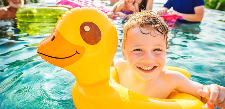 Junge badet mit aufblasbarer Ente im Swimmingpool